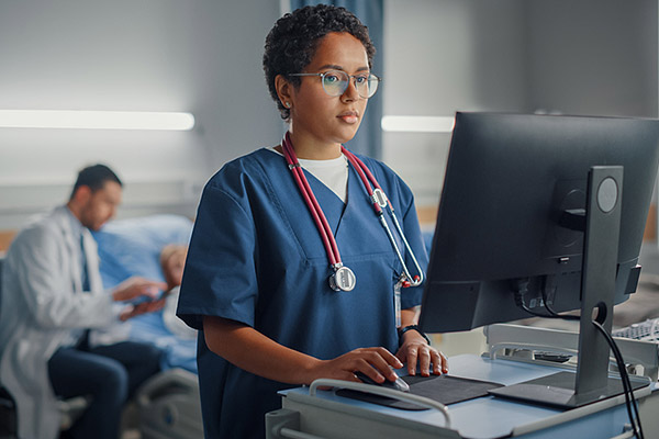 medical staff person working on a computer terminal in a hospital room