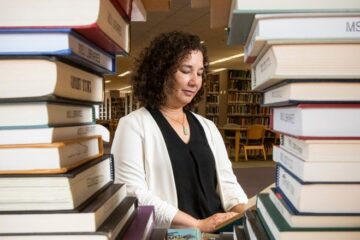 asian lady seen through two stacks of library books