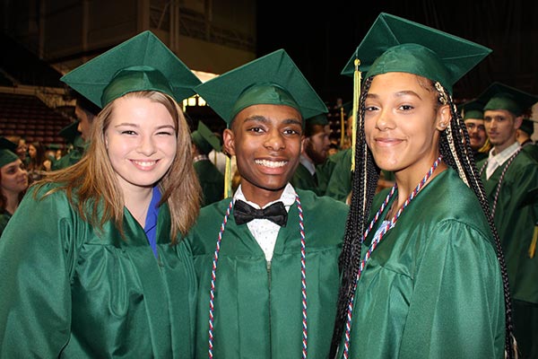 three high school graduates in green graduation gowns